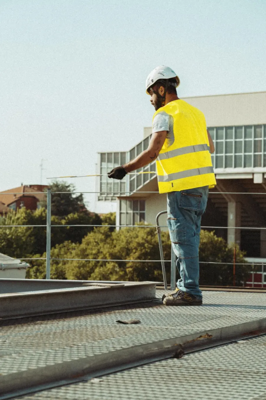 Tecnico Bricoli esegue un rilievo con il metro sulla copertura di un capannone